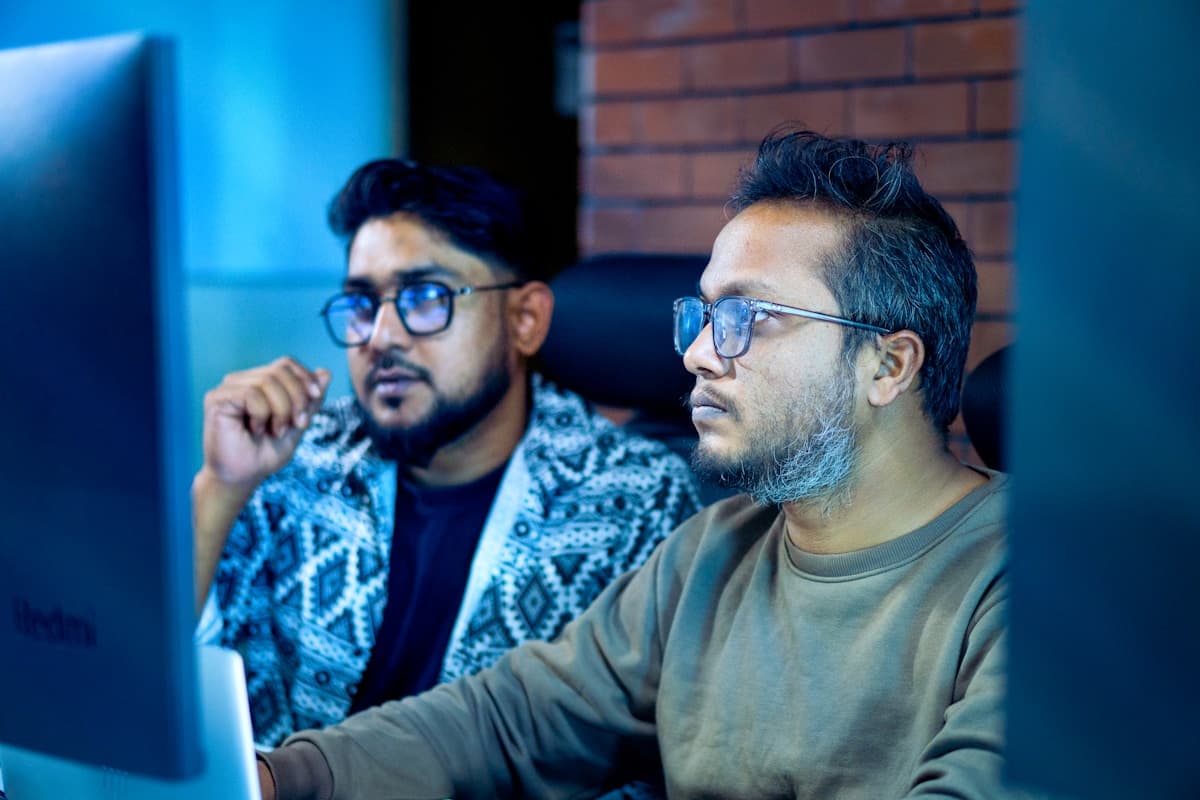 Software development team reviewing code on a large monitor